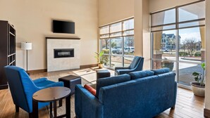 Una sala de estar moderna con chimenea, ventanas amplias y mobiliario azul.