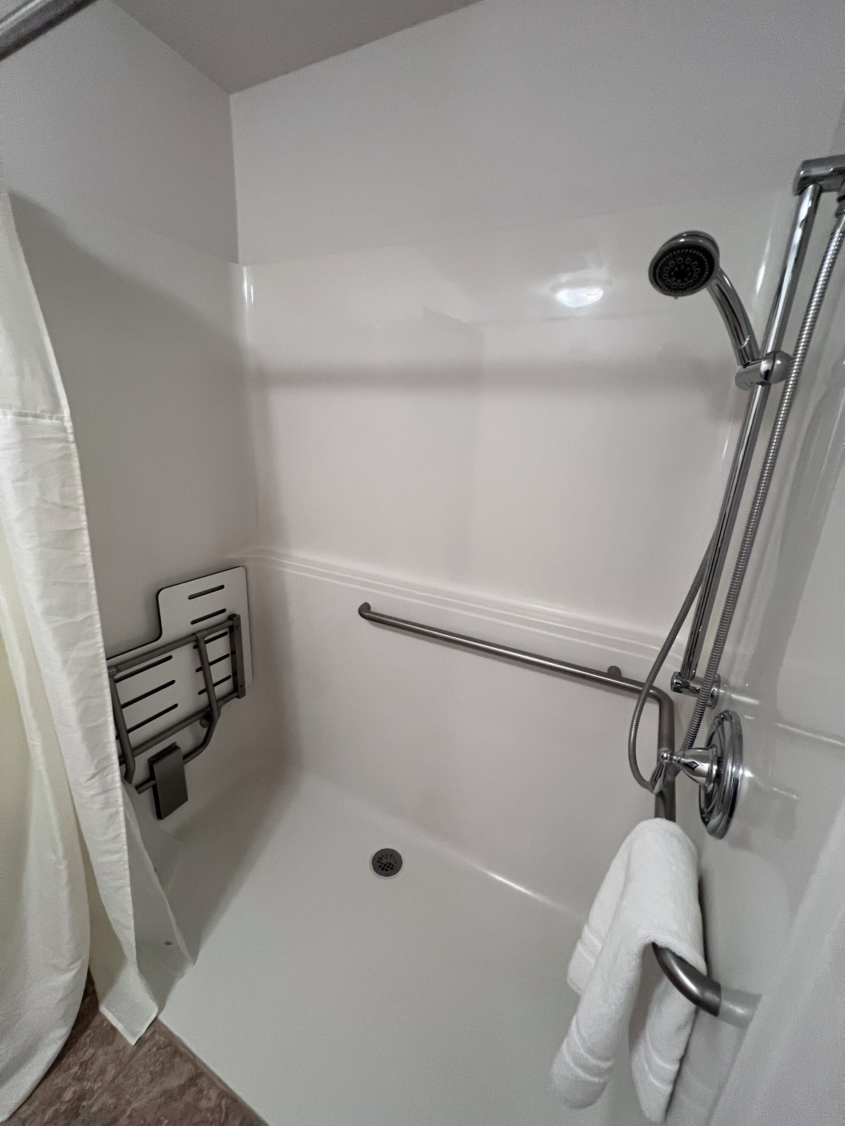 Un baño moderno con ducha, toallero y soporte para papel higiénico.