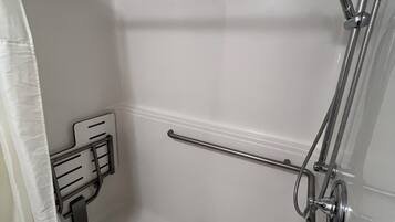 Un baño moderno con ducha, toallero y soporte para papel higiénico.