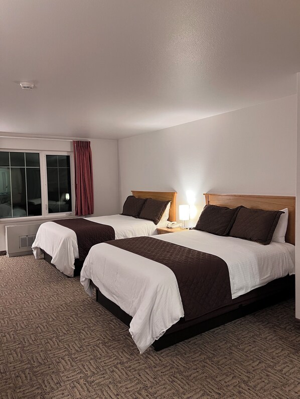A hotel room with two beds, a window with curtains, a bedside lamp, and a thermostat. - Hotel North Pole (North Pole)
