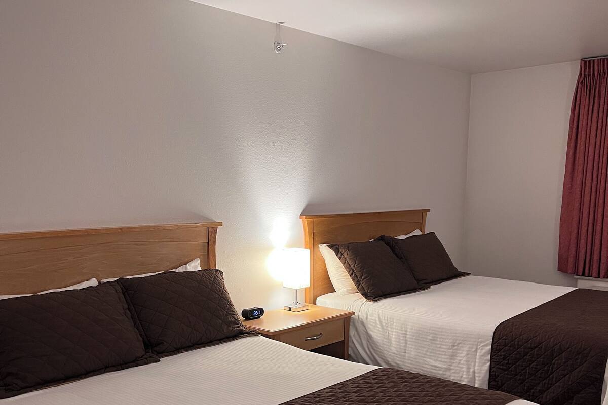 Ein Hotelzimmer mit zwei Betten, einem Nachttisch mit Lampe und einem roten Vorhang.