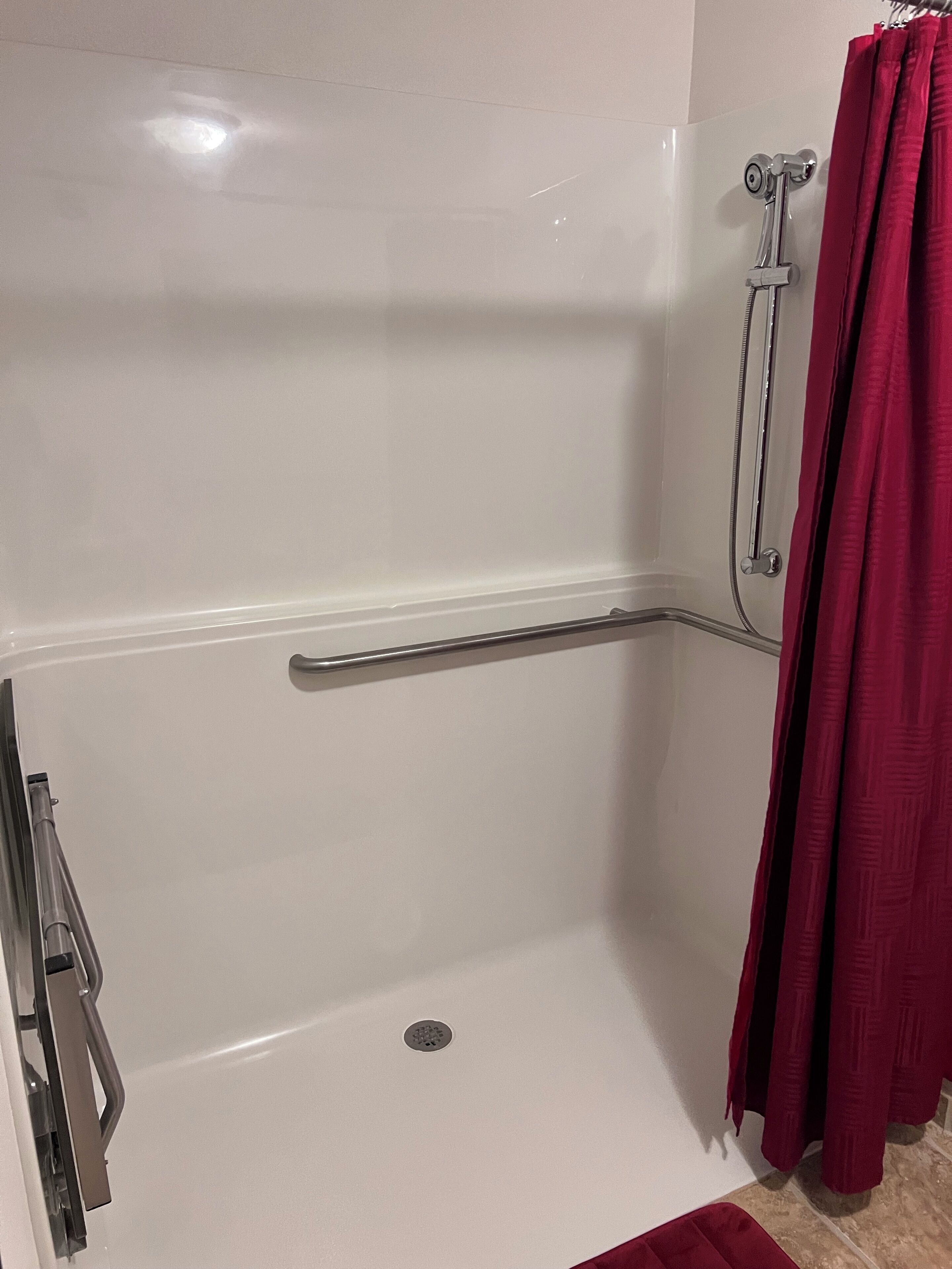 A white bathtub with a shower head and a grab bar.