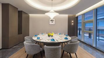 Une salle à manger moderne avec une table ronde, six chaises et un lustre central.