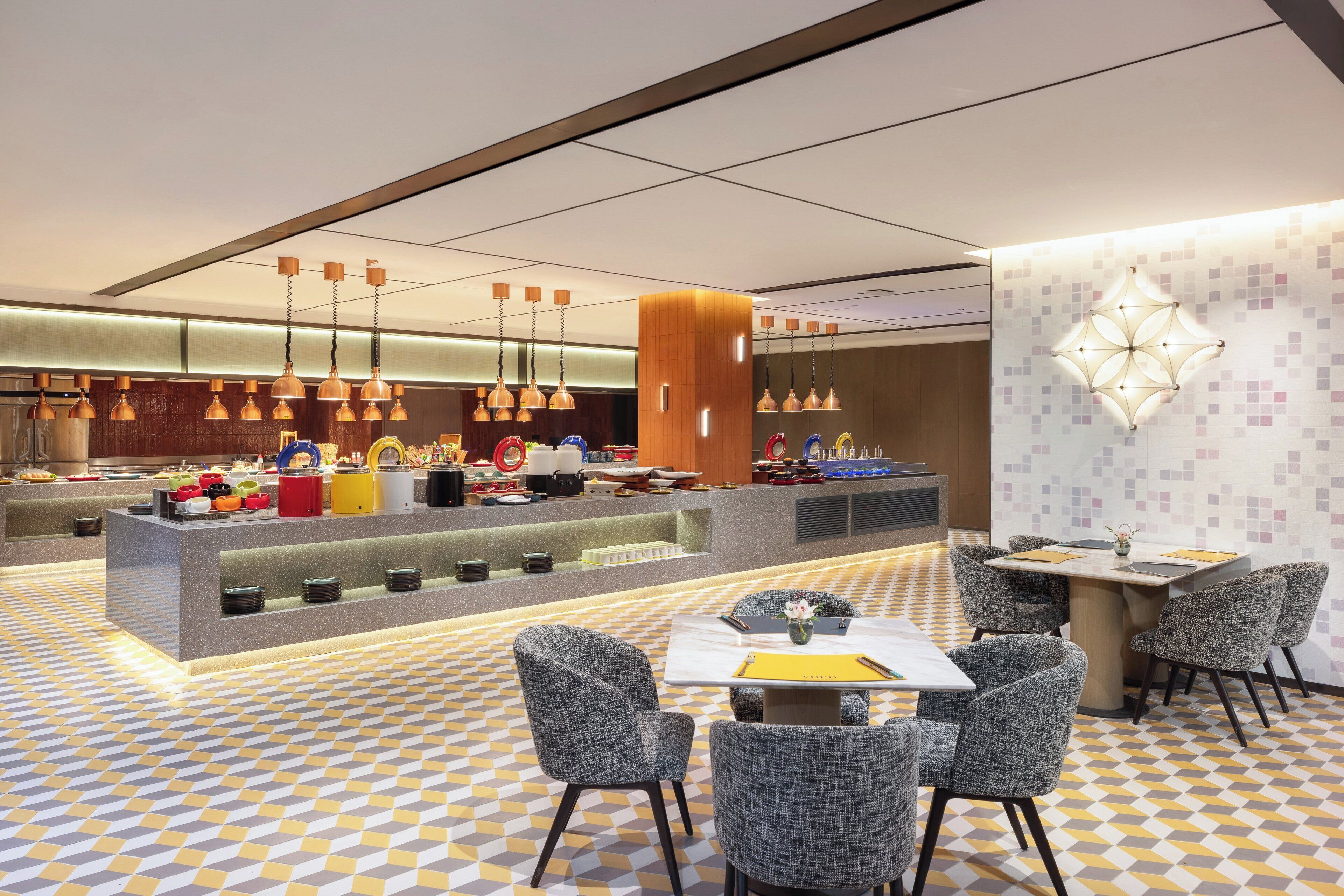 A modern hotel lobby with a check-in counter, seating area, and decorative lighting.