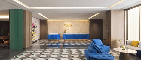 A modern lobby with a checkered floor, reception desk, and seating area.