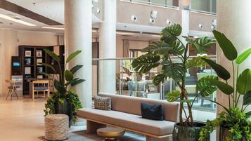 Un hall d’entrée moderne avec un canapé, des plantes en pot et un espace salon.