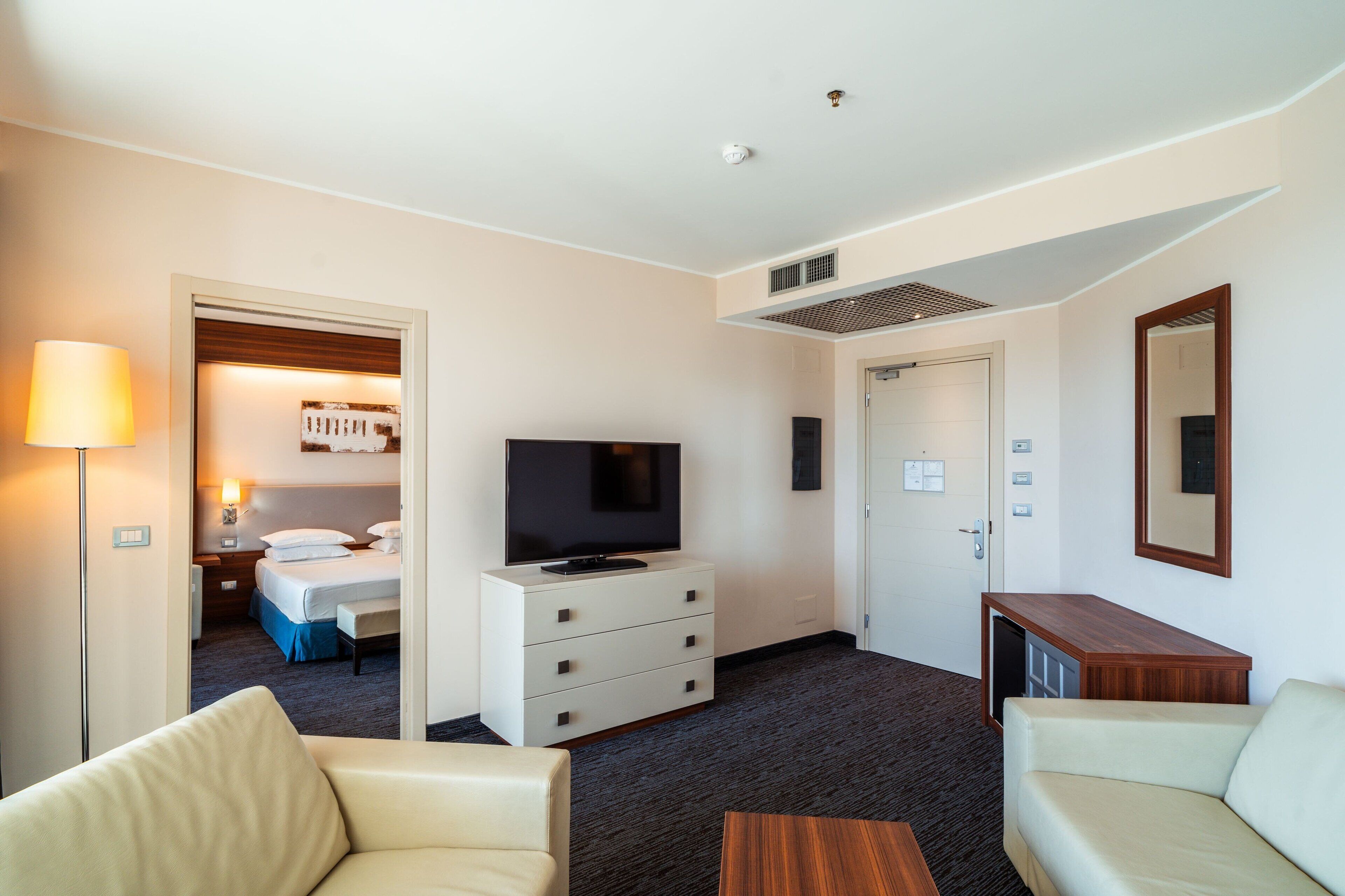 A hotel room with a bed, a TV, a desk, and a chair.