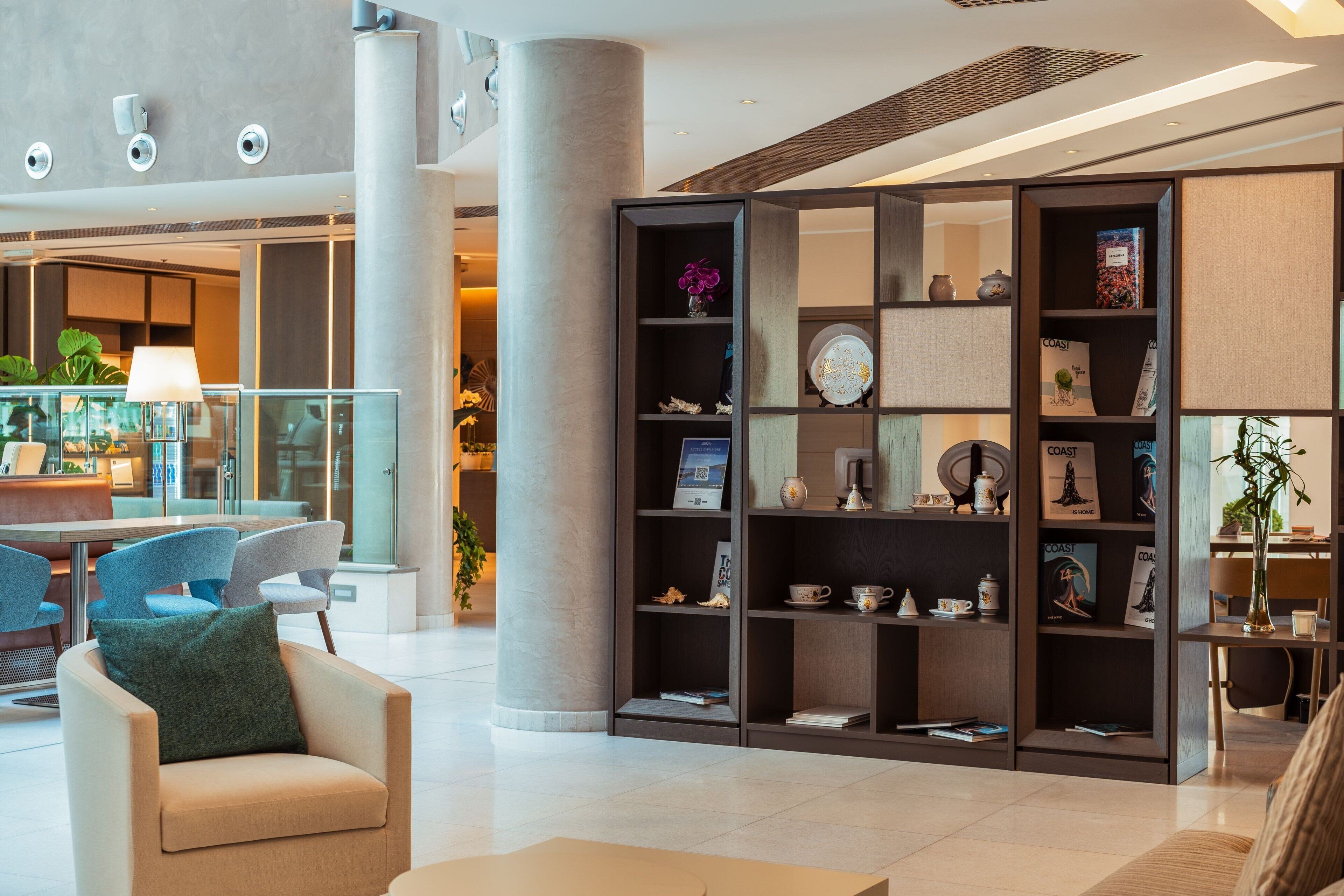 A modern lobby with a seating area, a large bookshelf, and a coffee table.