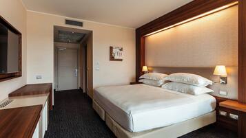 Ein Hotelzimmer mit einem großen Bett, einem Schreibtisch und einem Spiegel.
