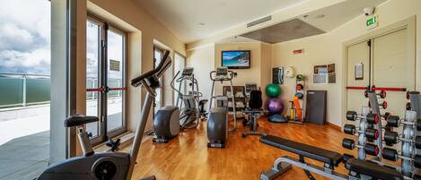 Un gimnasio con máquinas de cardio, equipo de levantamiento de pesas y pelotas de ejercicio.