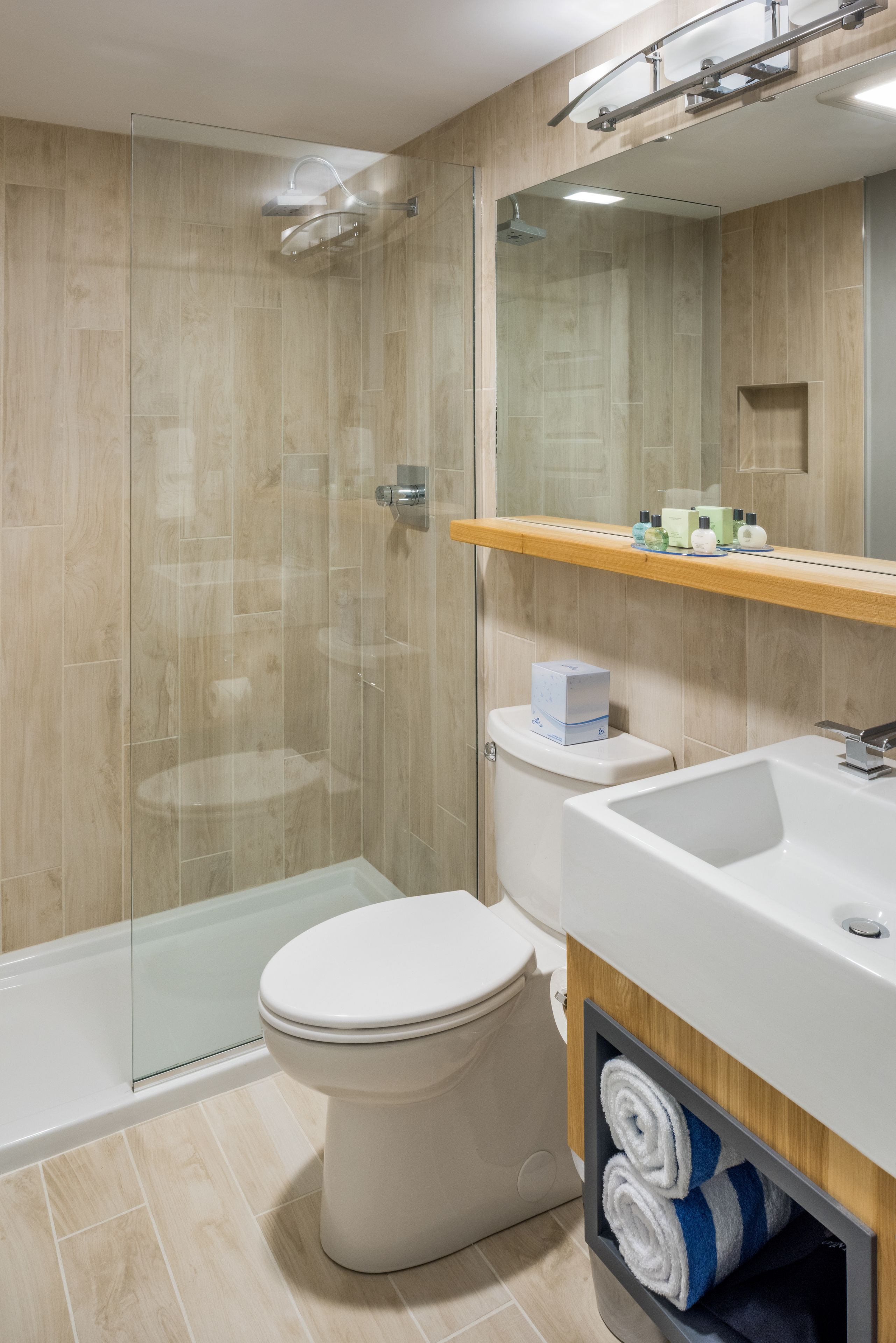 Ein modernes Badezimmer mit einer Duschkabine, einer Toilette und einem Waschtisch mit Waschbecken und Spiegel.