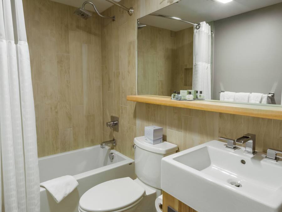 A modern bathroom with a bathtub, toilet, and dual sinks.