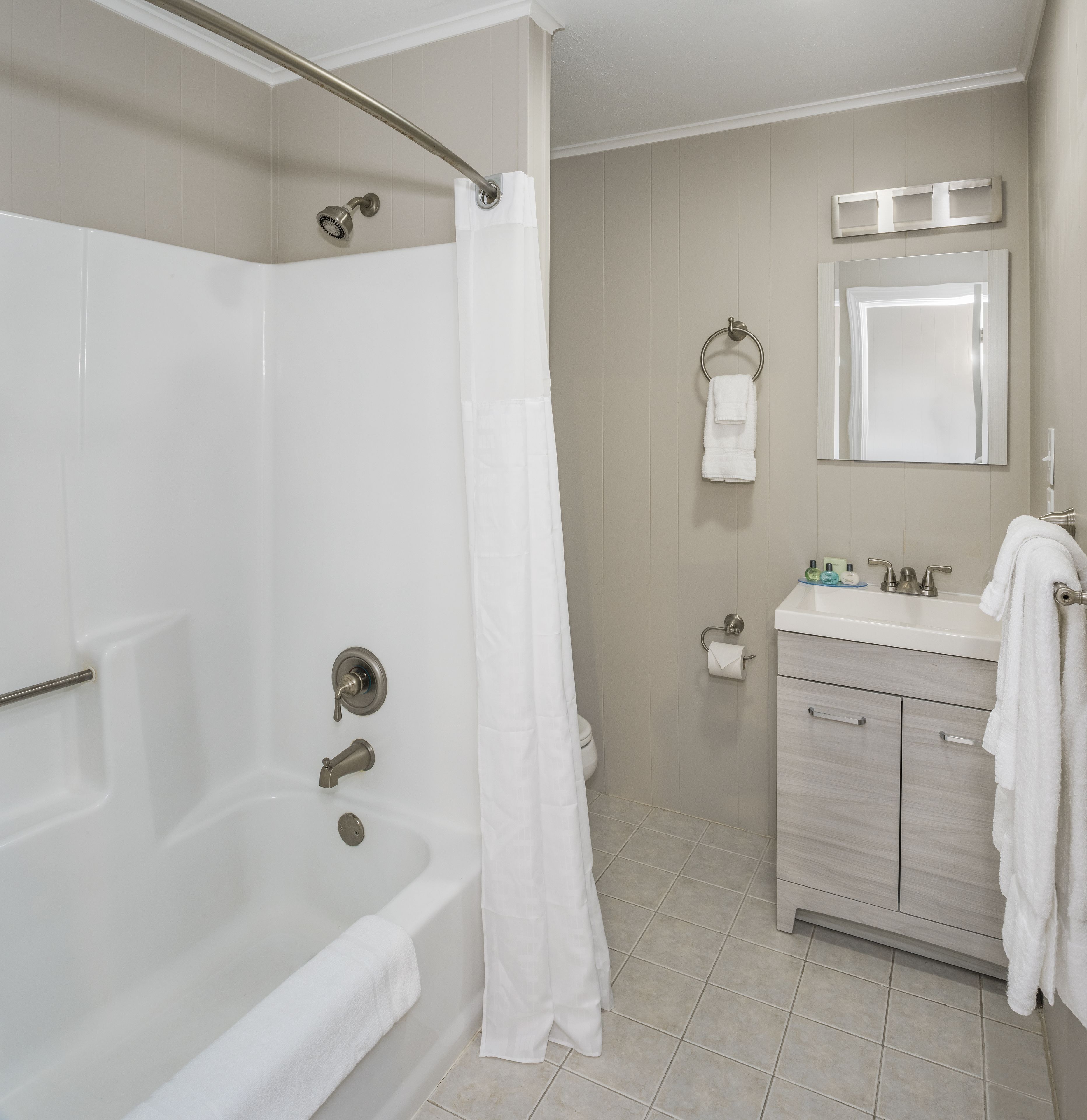 A bathroom with a bathtub, a shower, a toilet, a sink, and a mirror.