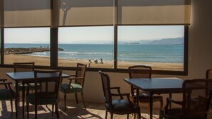 A room with large windows overlooking a beach, furnished with wooden tables and chairs. - Sicania (Cullera)