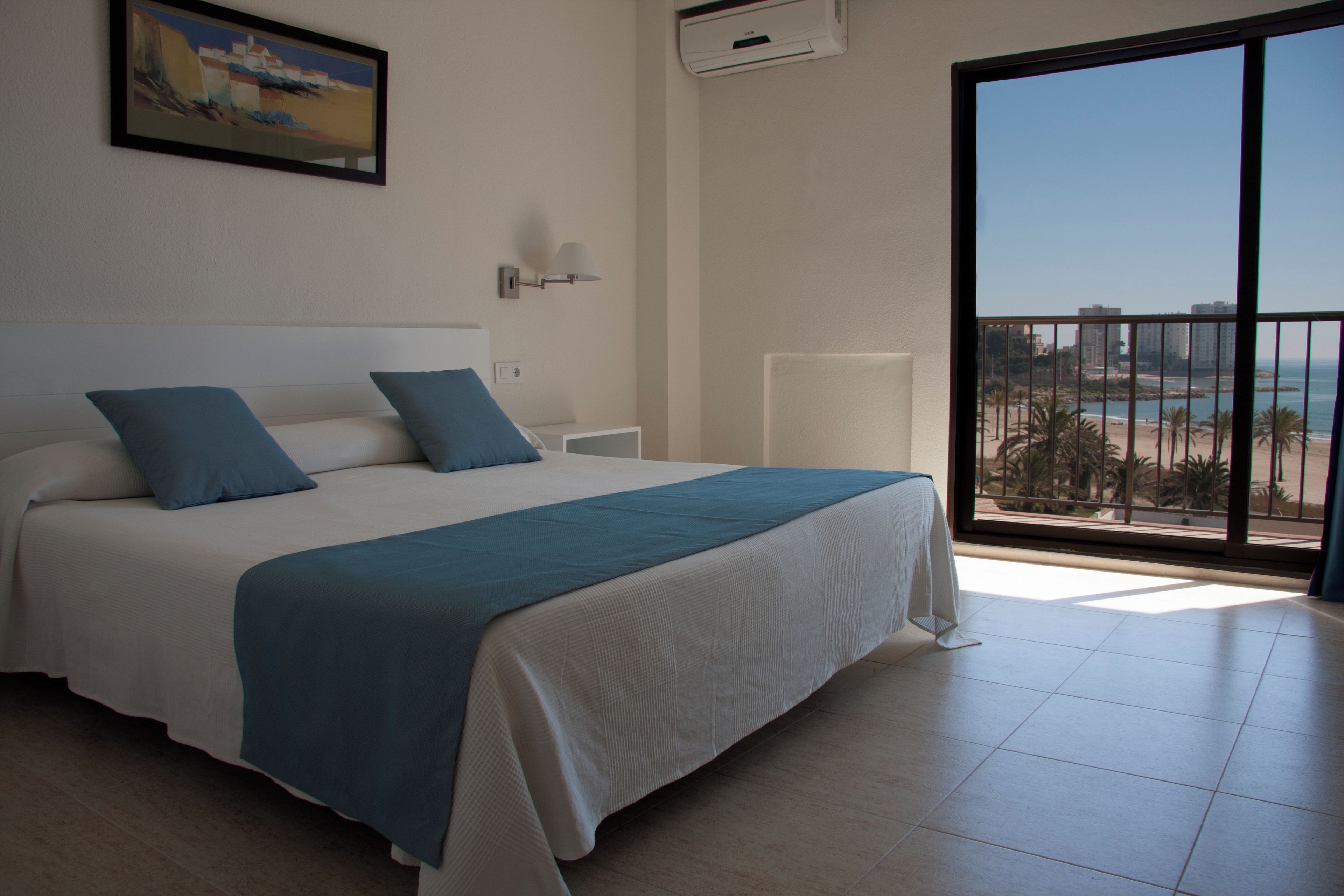 Una camera d'albergo con un letto grande, vista sulla spiaggia e un balcone.