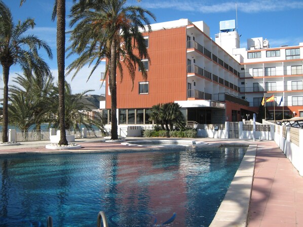 A hotel with a swimming pool, palm trees, and a modern building with balconies. - Sicania (Cullera)