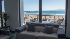 Un balcon avec un canapé, des chaises et une table, donnant sur une plage.