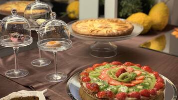 Un tavolo con dolci assortiti, tra cui una crostata di frutta e una fetta di torta su un piatto.