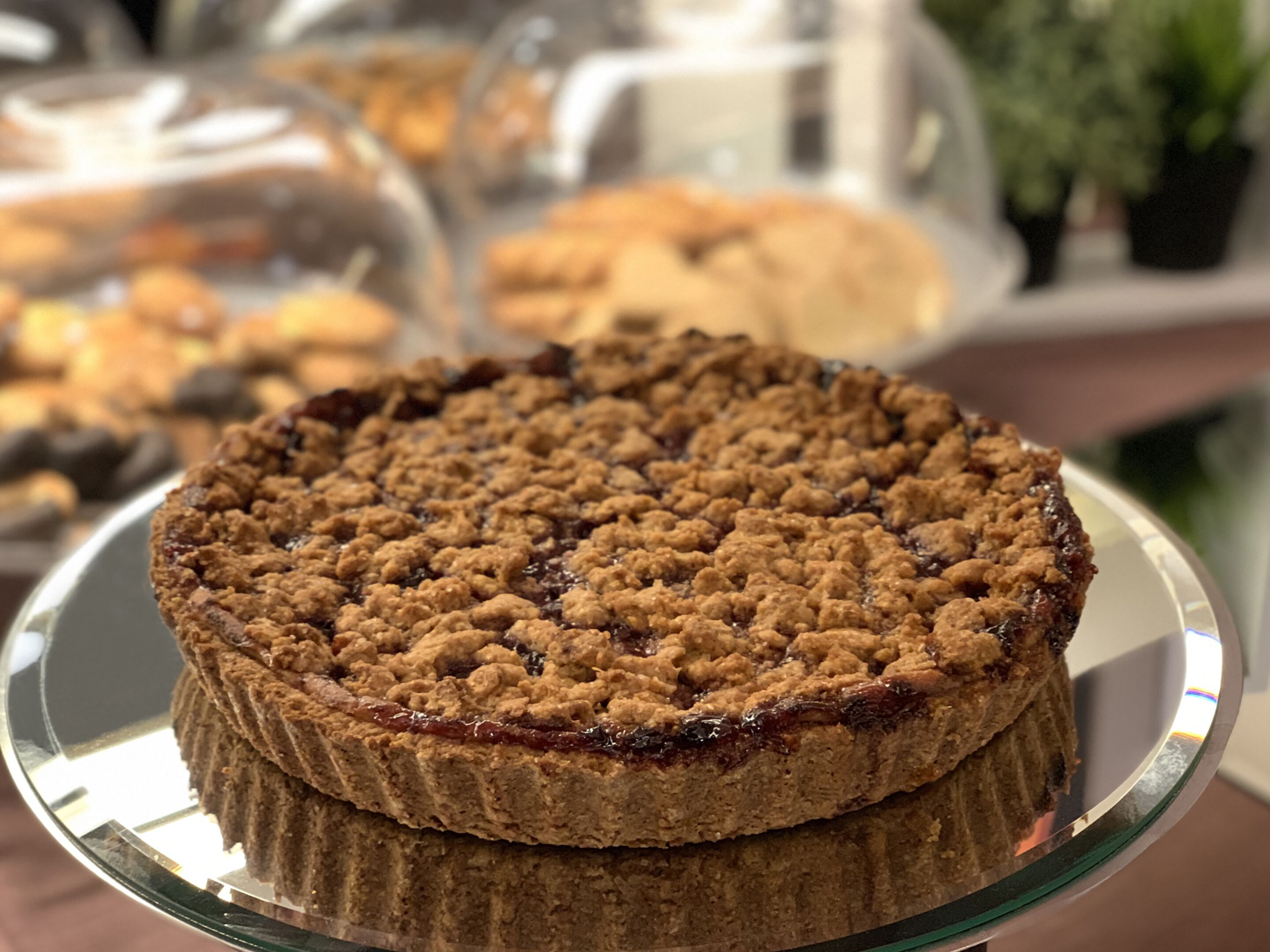 A round cake with a crumbly topping on a glass plate.