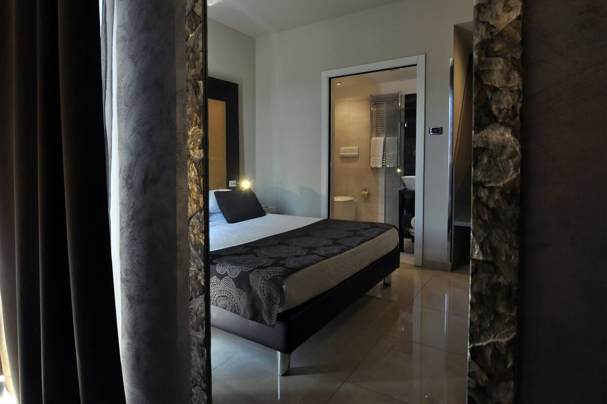 Quarto moderno com uma cama grande, um closet espaçoso e um banheiro com chuveiro de vidro.