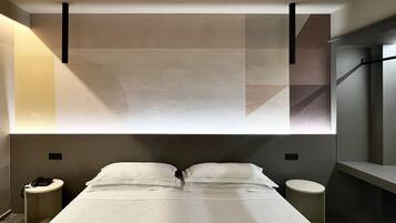 Habitació d'hotel moderna amb un llit gran, dues taules de nit i una paret amb un disseny geomètric.