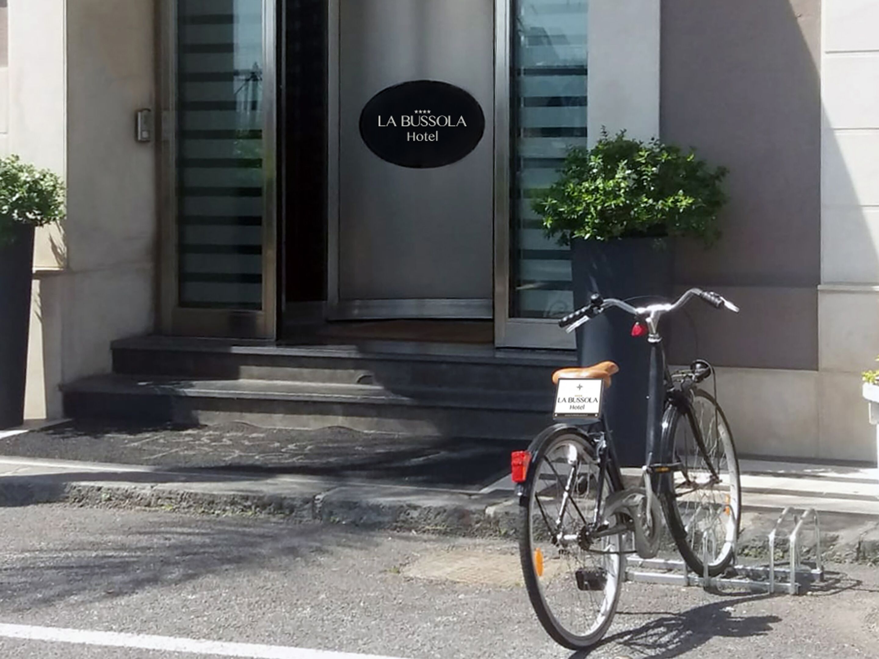 A bicycle parked in front of a building with a sign reading "LA BUSSOLOA Hotel".