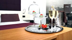 A tray with two champagne flutes and a dessert set on a wooden table in a hotel room.