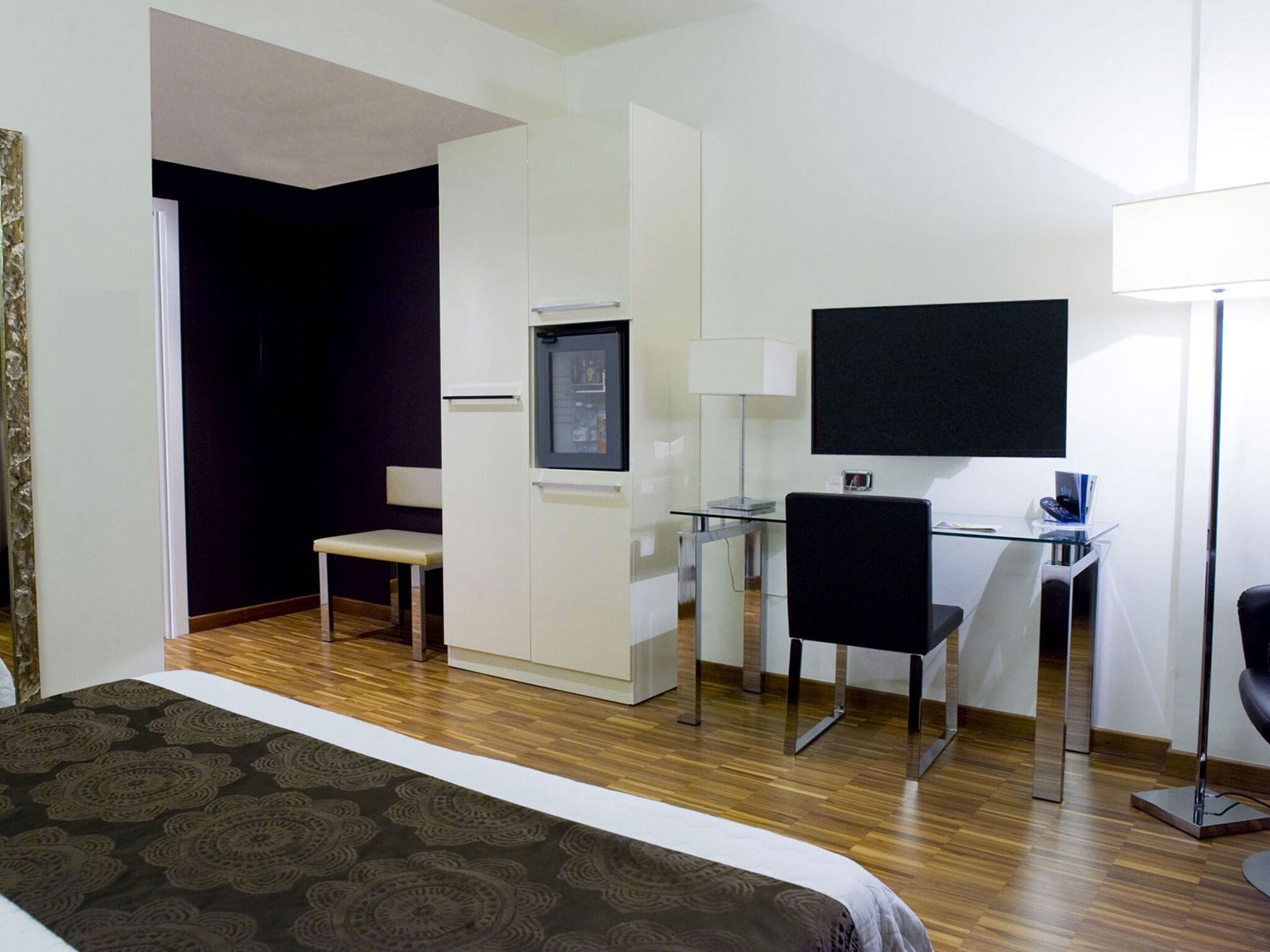 Une chambre d’hôtel comprenant un lit, un bureau avec une chaise, une télévision et une lampe.