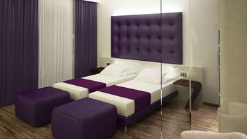 Una habitación de hotel moderna con una cama grande, dos mesitas de noche y una zona de estar con otomanas moradas.