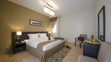 Ein Hotelzimmer mit Bett, Nachttisch, Lampe, Stuhl und einem kleinen Tisch mit Tablett.