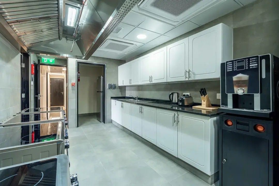 A modern kitchen with white cabinets, stainless steel appliances, and a coffee machine.