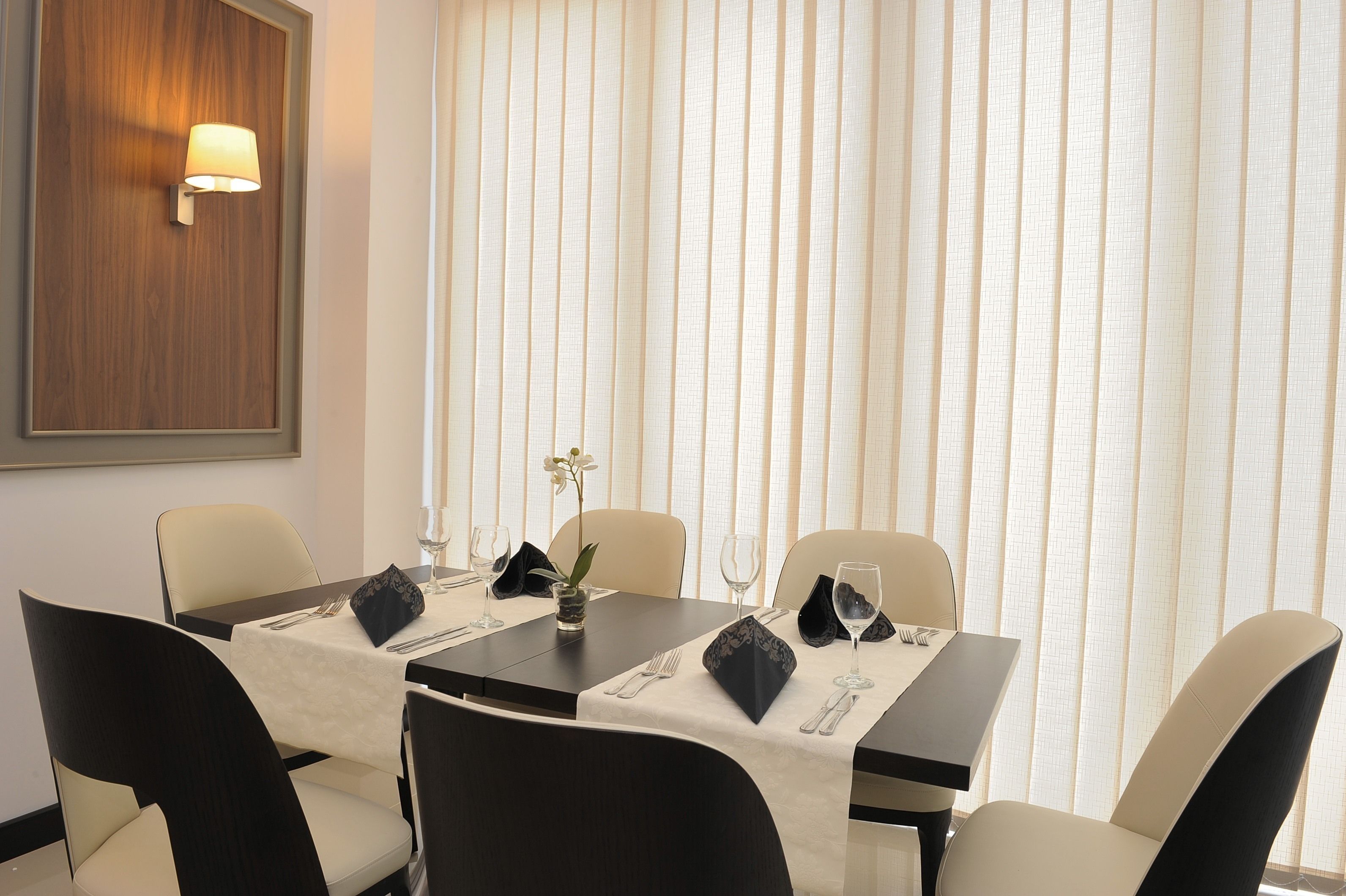 A dining area with a table set for four, including place settings and a vase of flowers.