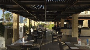 An outdoor patio with wicker furniture, air conditioning units, and a bar area. - The Apartments Dubai World Trade Centre (Dubai)