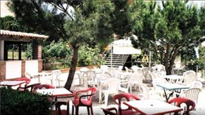 An outdoor seating area with white plastic tables and chairs, surrounded by trees. - Hostal Monasterio de Rueda (Sastago)