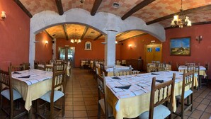 A restaurant with multiple tables and chairs, brick arches, and a tiled floor. - Hostal Monasterio de Rueda (Sastago)