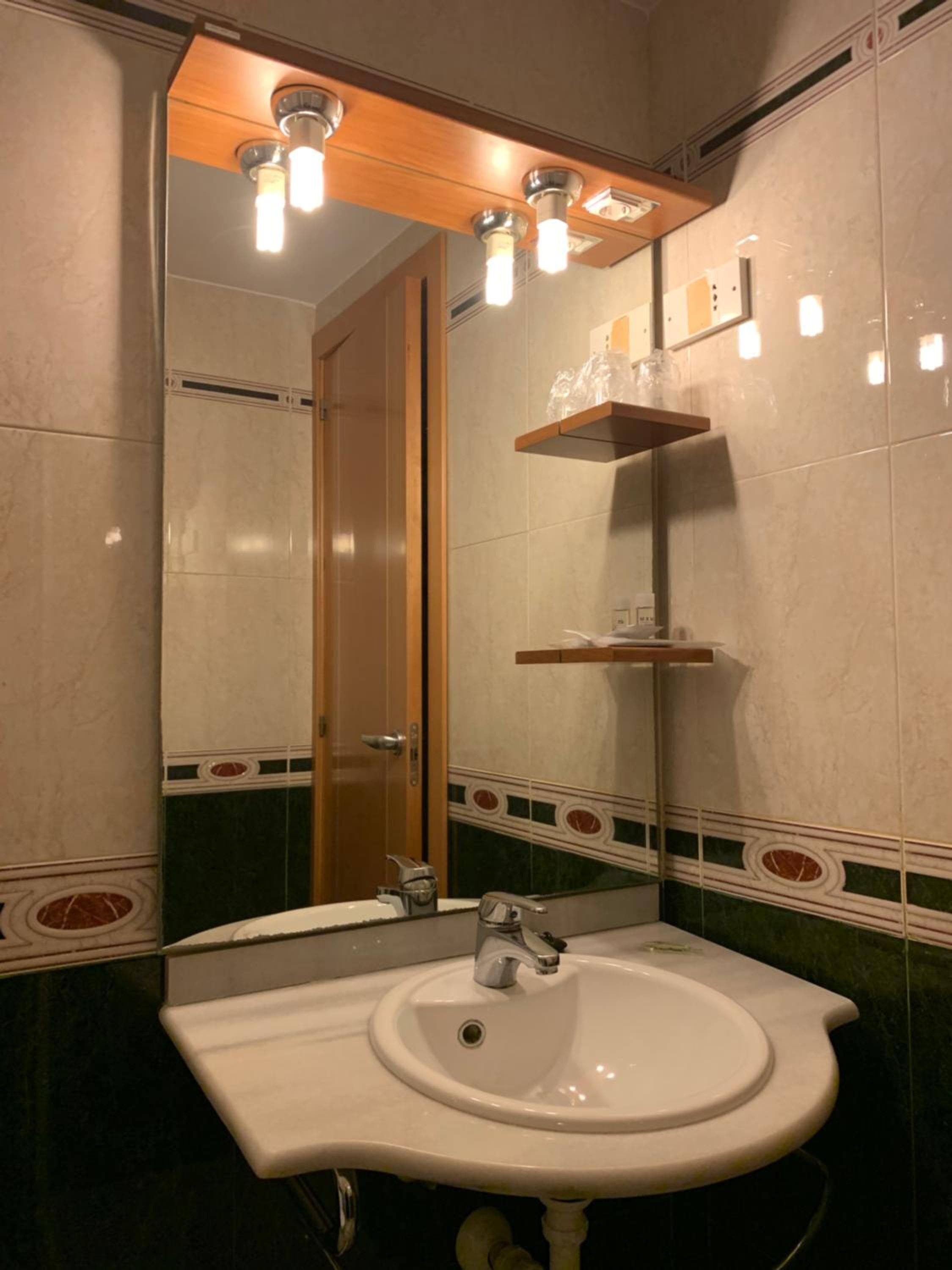 A bathroom with a white sink, a mirror, and a wooden door.