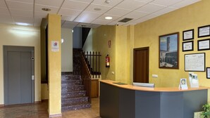 A reception area with a counter, a fire extinguisher, a staircase, and a door. - Hostal Monasterio de Rueda (Sastago)