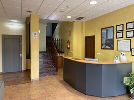 Zona de recepción con mostrador, extintor, escalera y puerta.