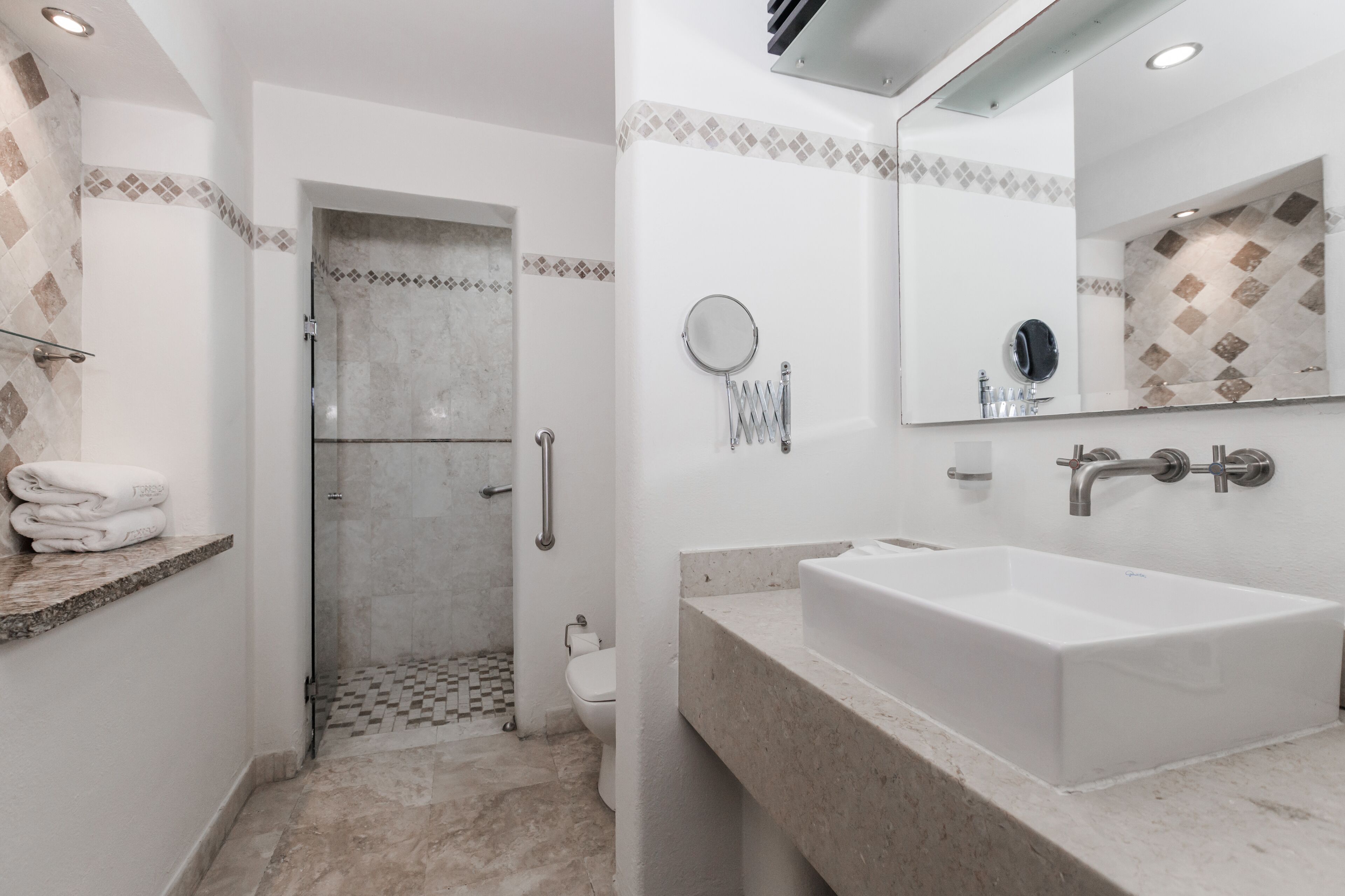 A bathroom with a large sink, a mirror, and a shower area.