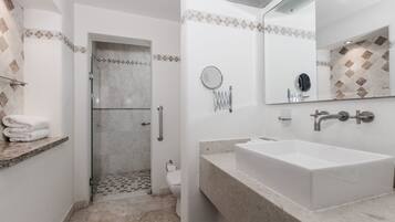 Un baño con un lavamanos grande, un espejo y una zona de ducha.