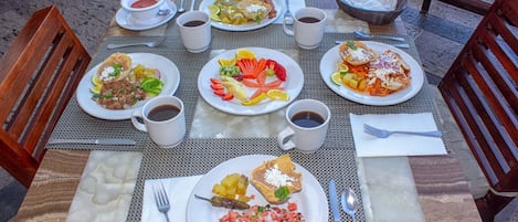 Una mesa dispuesta con diferentes platos de comida, tazas de café y cubiertos.