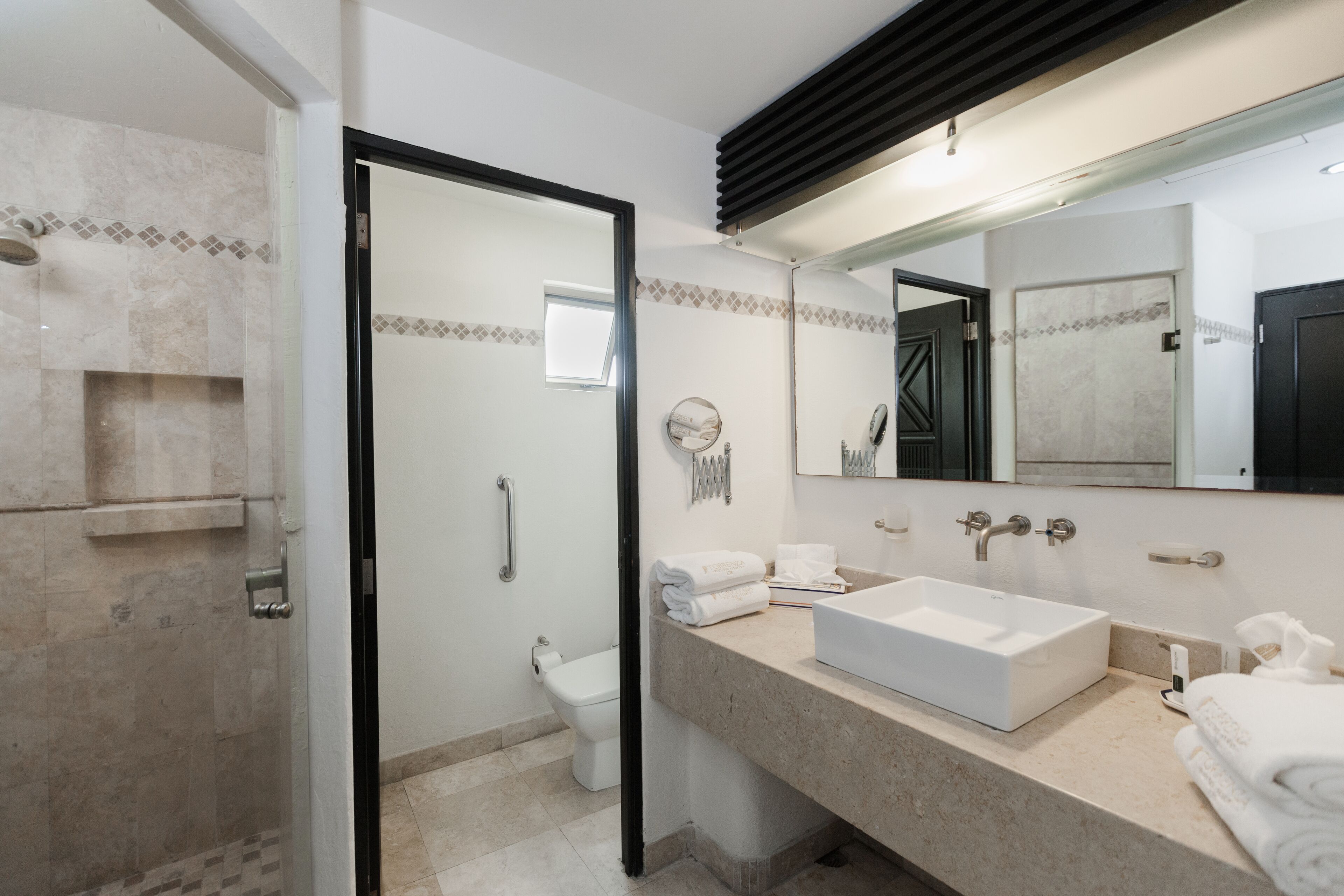 Un baño moderno con cabina de ducha de vidrio, un lavabo blanco y un espejo grande.