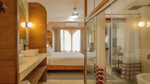 A modern hotel room with a bed, a glass shower enclosure, a vanity with a mirror, and a ceiling fan. - Hotel Amaca Puerto Vallarta - Adults Only (Puerto Vallarta)