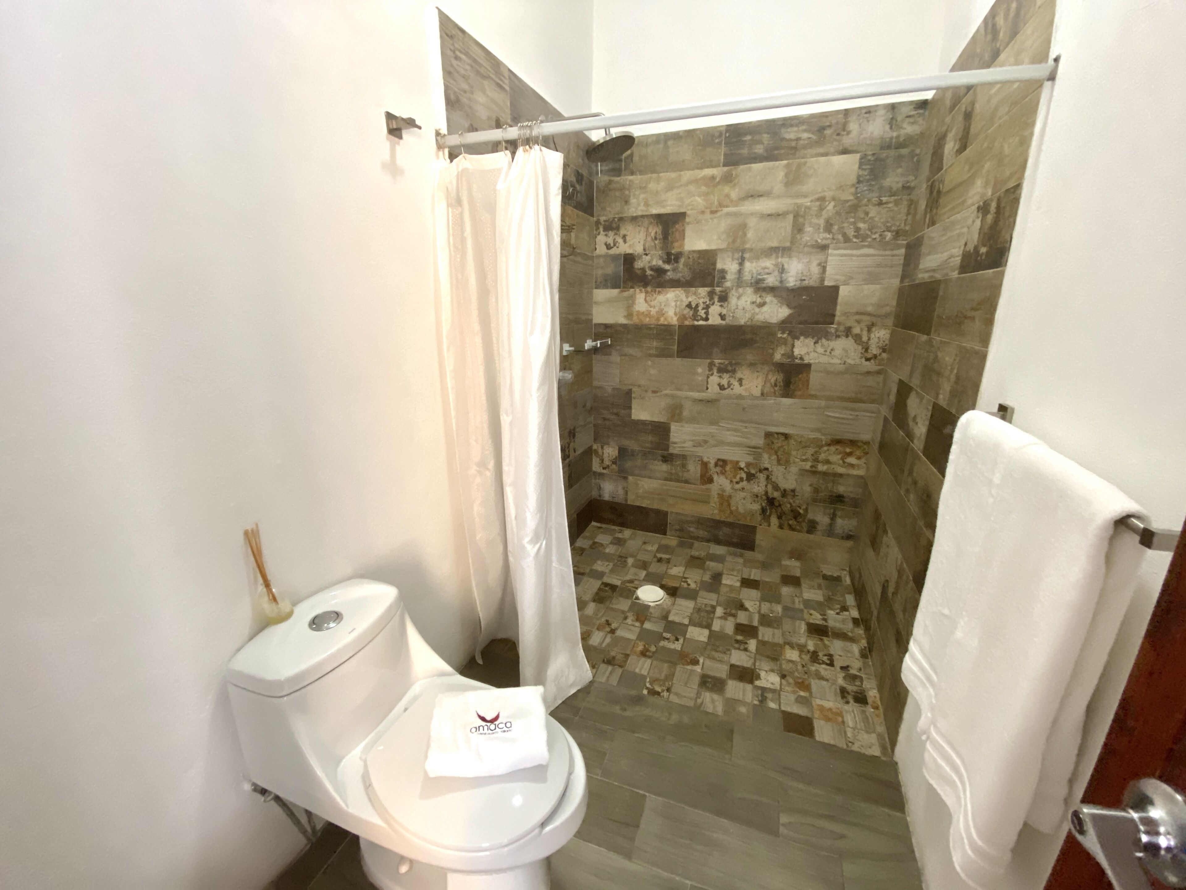 A bathroom with a shower, a toilet, and a checkered floor.