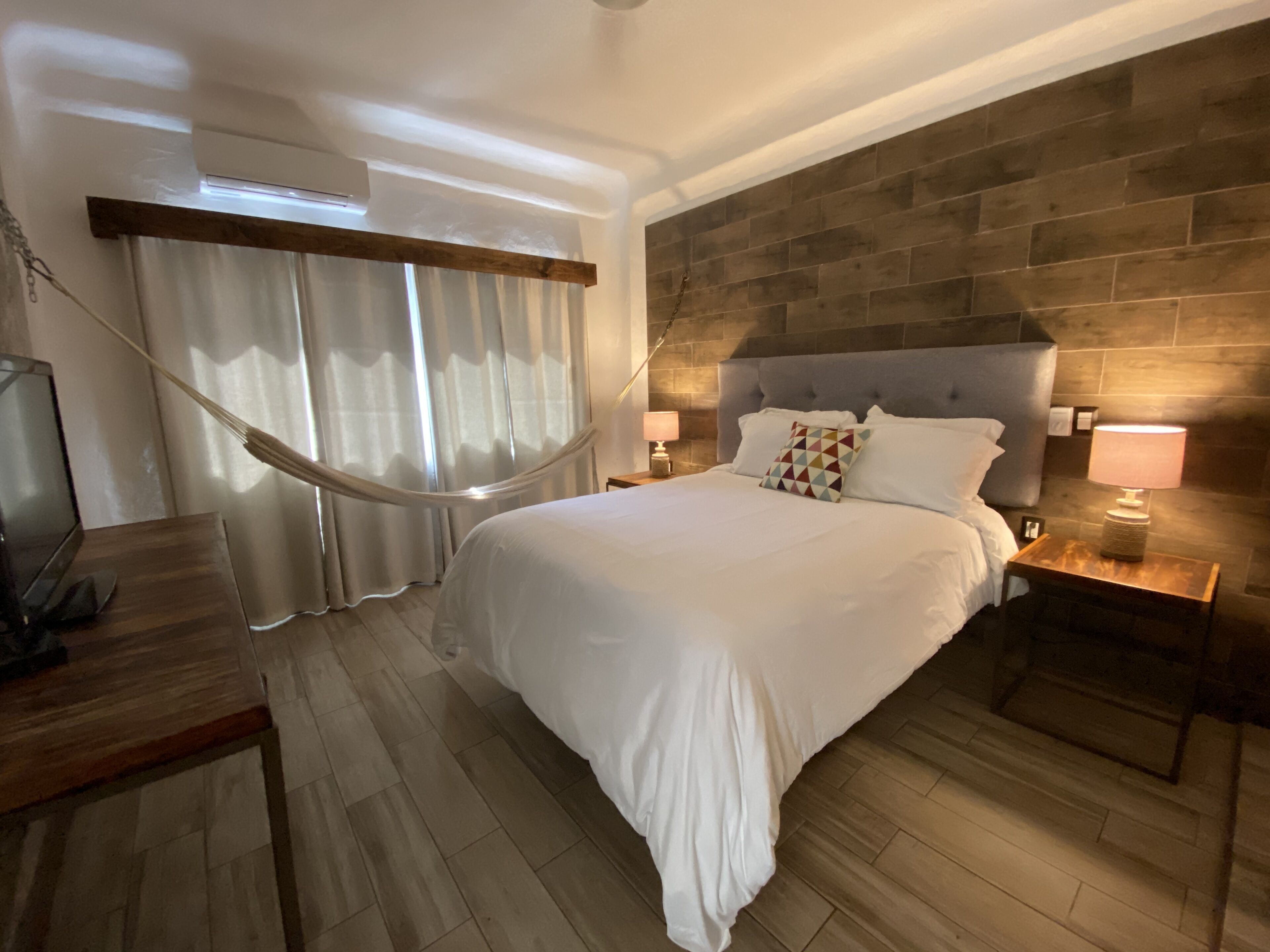 Una habitación de hotel moderna con una cama grande, suelo de madera y una pared de acento de piedra.