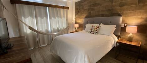 Una habitación de hotel moderna con una cama grande, suelo de madera y una pared de acento de piedra.