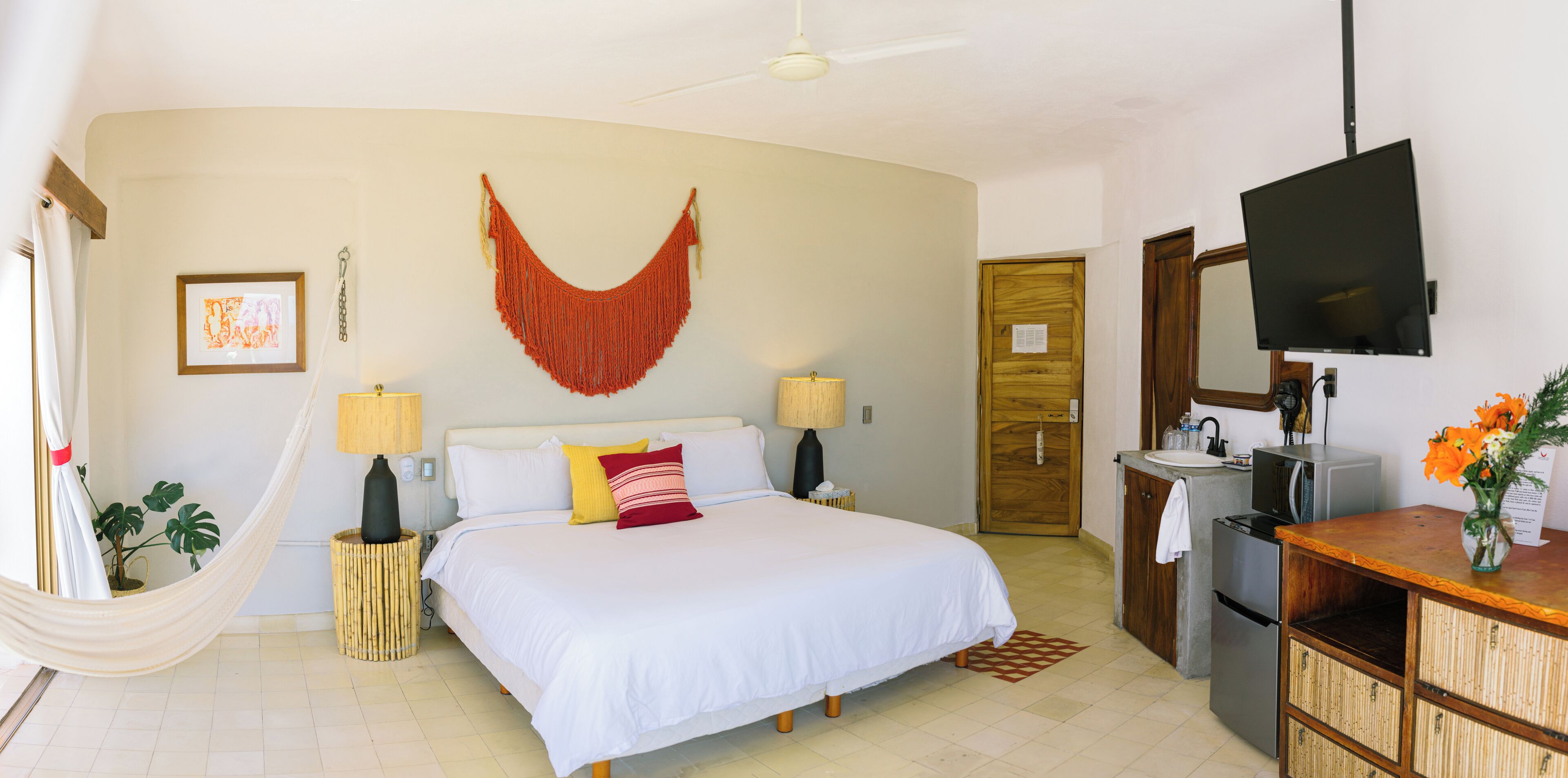Une chambre d’hôtel comprenant un lit, des lampes de chevet, une télévision, une armoire en bois et un miroir.