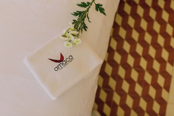 Una toalla con un logotipo y texto, sobre una superficie con fondo de baldosas estampadas.