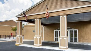 A building with a covered entrance, columns, and American flags. - Econo Lodge Pine Bluff (Pine Bluff)