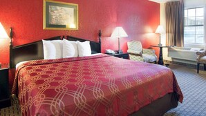 A hotel room with a large bed, two bedside tables, a chair, and a window with curtains. - Econo Lodge Pine Bluff (Pine Bluff)
